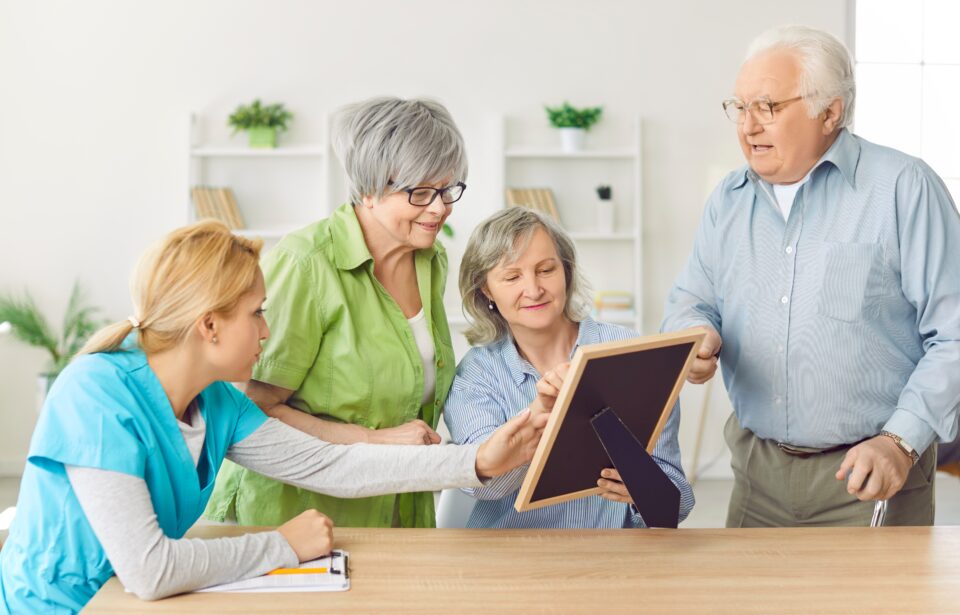 Senior people and care assistant in retirement home holding photo frame, old age home nursing facilities, older adults in happy supportive community, medical skilled geriatrician care, assisted living