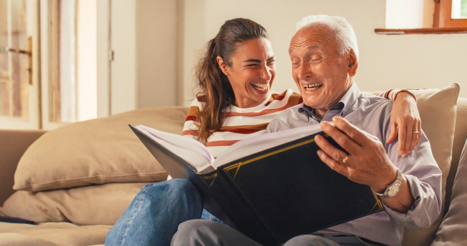 Senior male looking at photo album with adult daughter
