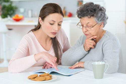 Adult daughter and aging mother reviewing document at table