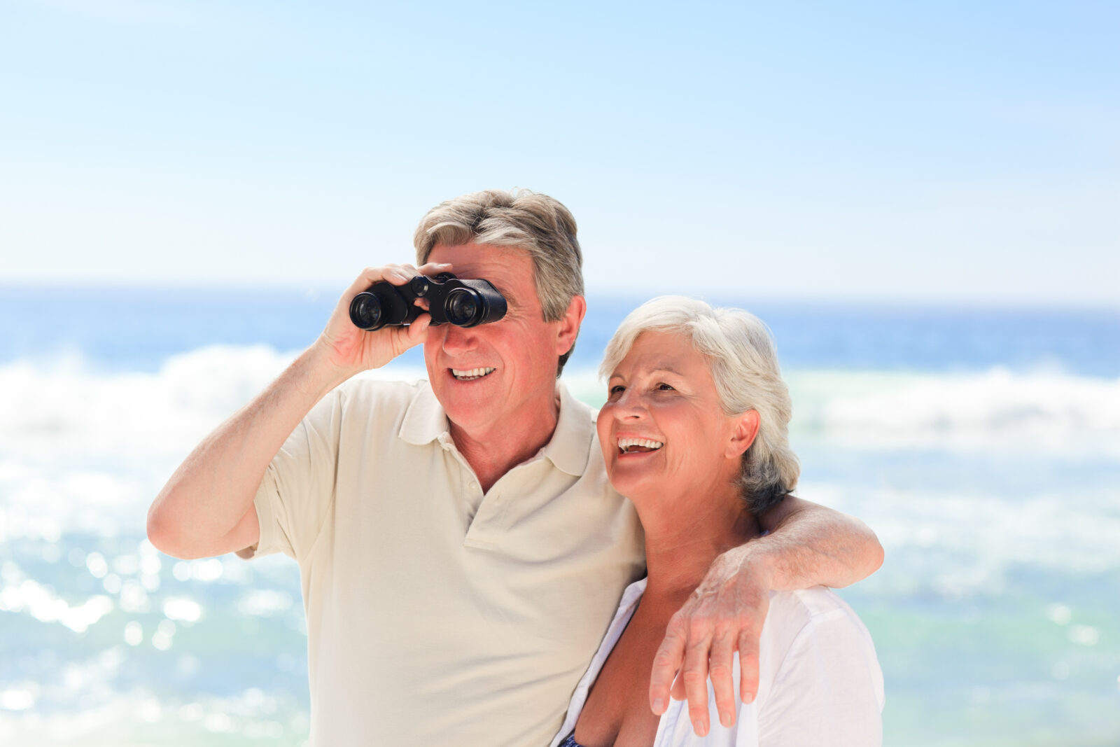 senior couple at ocean with binoculars